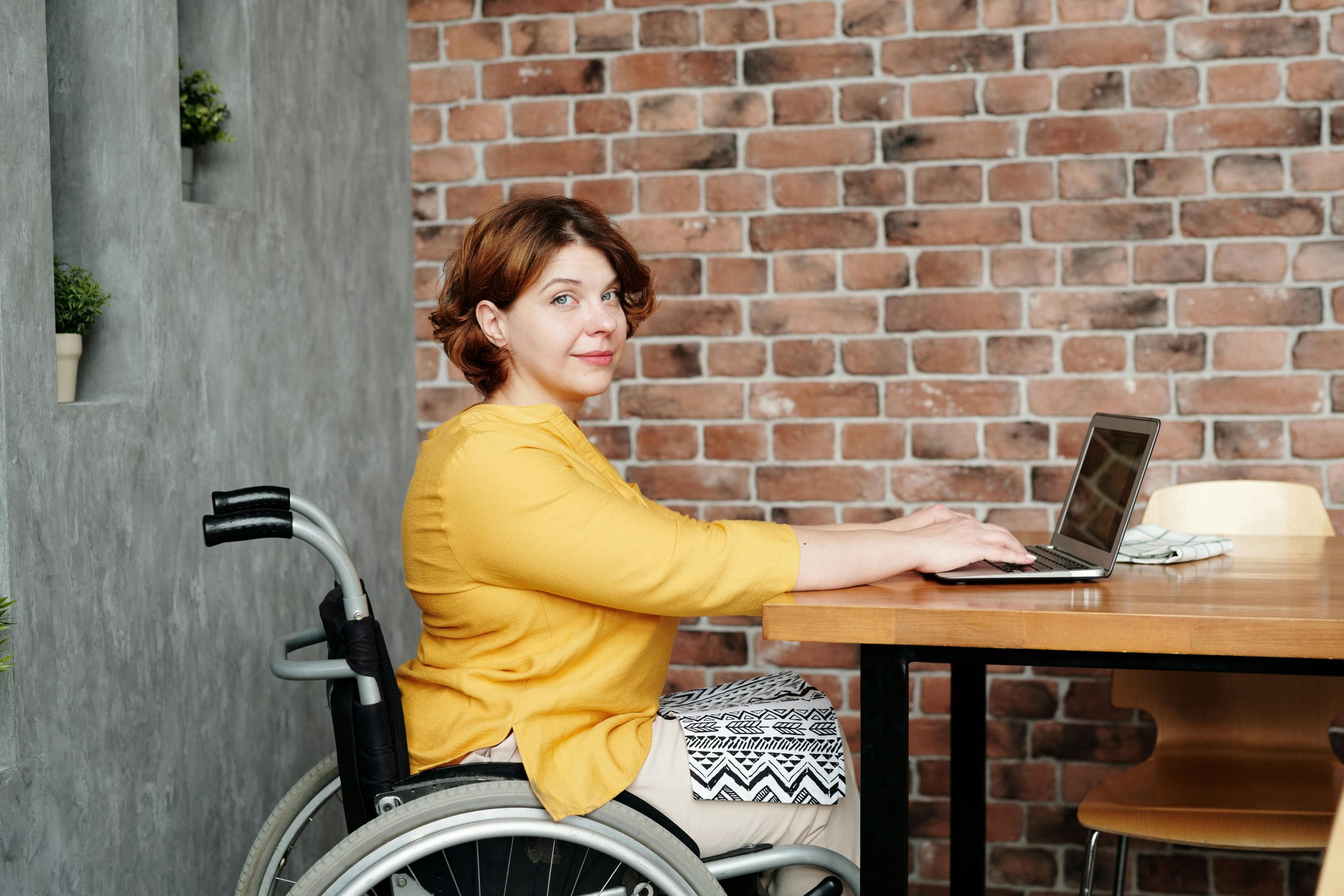 woman in a wheelchair typing on a laptop